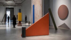 Visitatori osservano un'installazione contemporanea composta da oggetti e forme colorate in una galleria